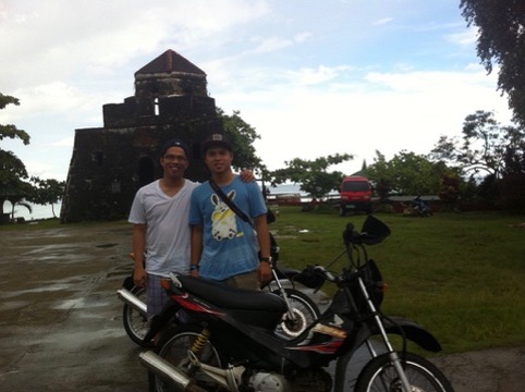 Travelers beside a motorbike at a stone landmark in Bohol