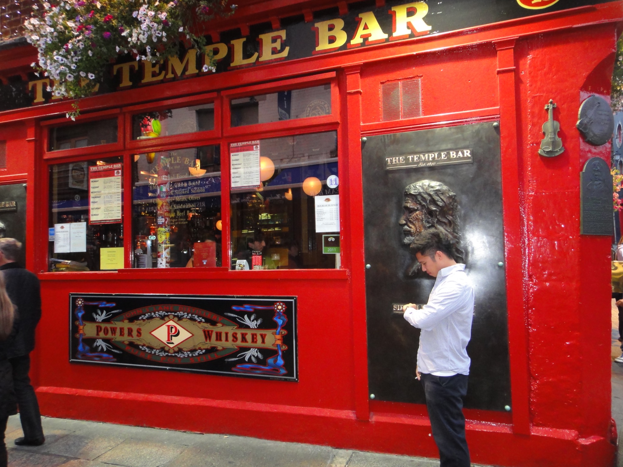 Traveler standing outside the bright red Temple Bar in Dublin