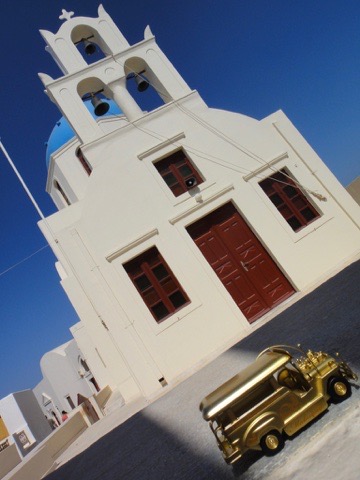 Golden jeepney beside a whitewashed church in Santorini